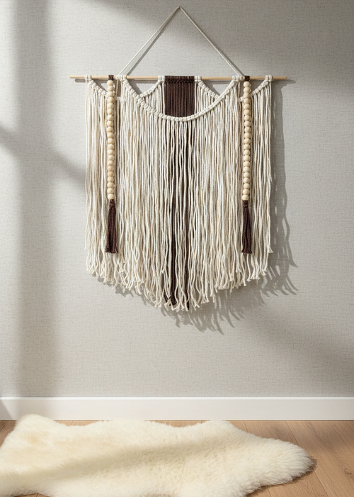 Woven wall hanging with fringe on a plain wall, with a fur rug on the floor.